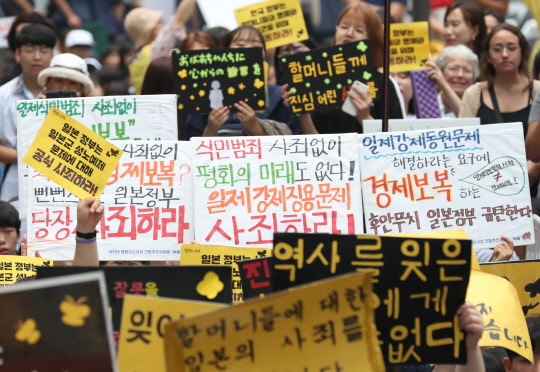 17일 서울 종로구 옛 일본대사관 앞에서 열린 제1396차 일본군 성노예제 문제 해결을 위한 정기 수요집회에서 참가자들이 역사 사죄 촉구 및 경제 보복을 규탄하는 피켓을 들고 구호를 외치고 있다.   연합뉴스